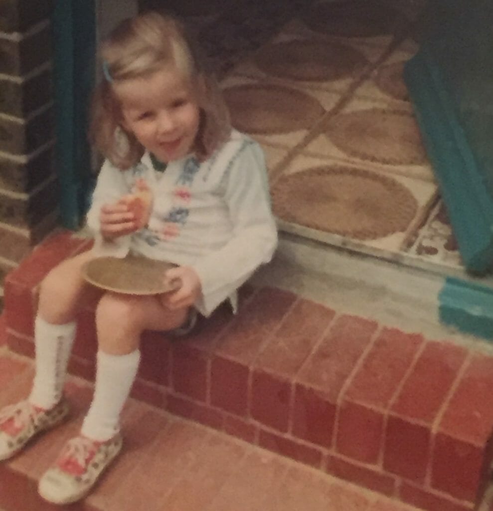 CHECT photo - Zoe Weeks as a girl, sitting on a step eating some food