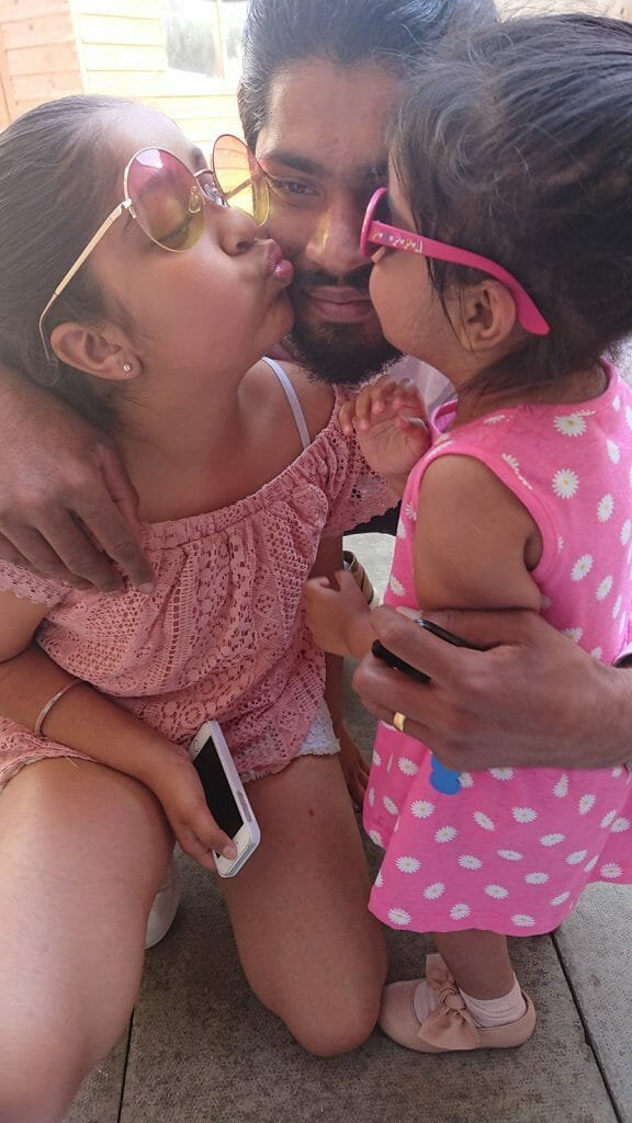 CHECT photo - Kulvir with his two daughters, they are both kissing one of his cheeks