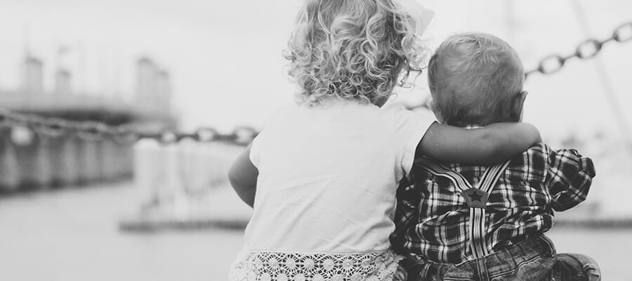 CHECT Photo - stock photo of two young children with their back to the camera, one has their arm around the other.