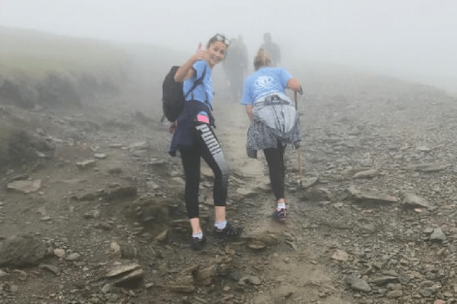 A group of young women hiking up a mountain on a super foggy day.