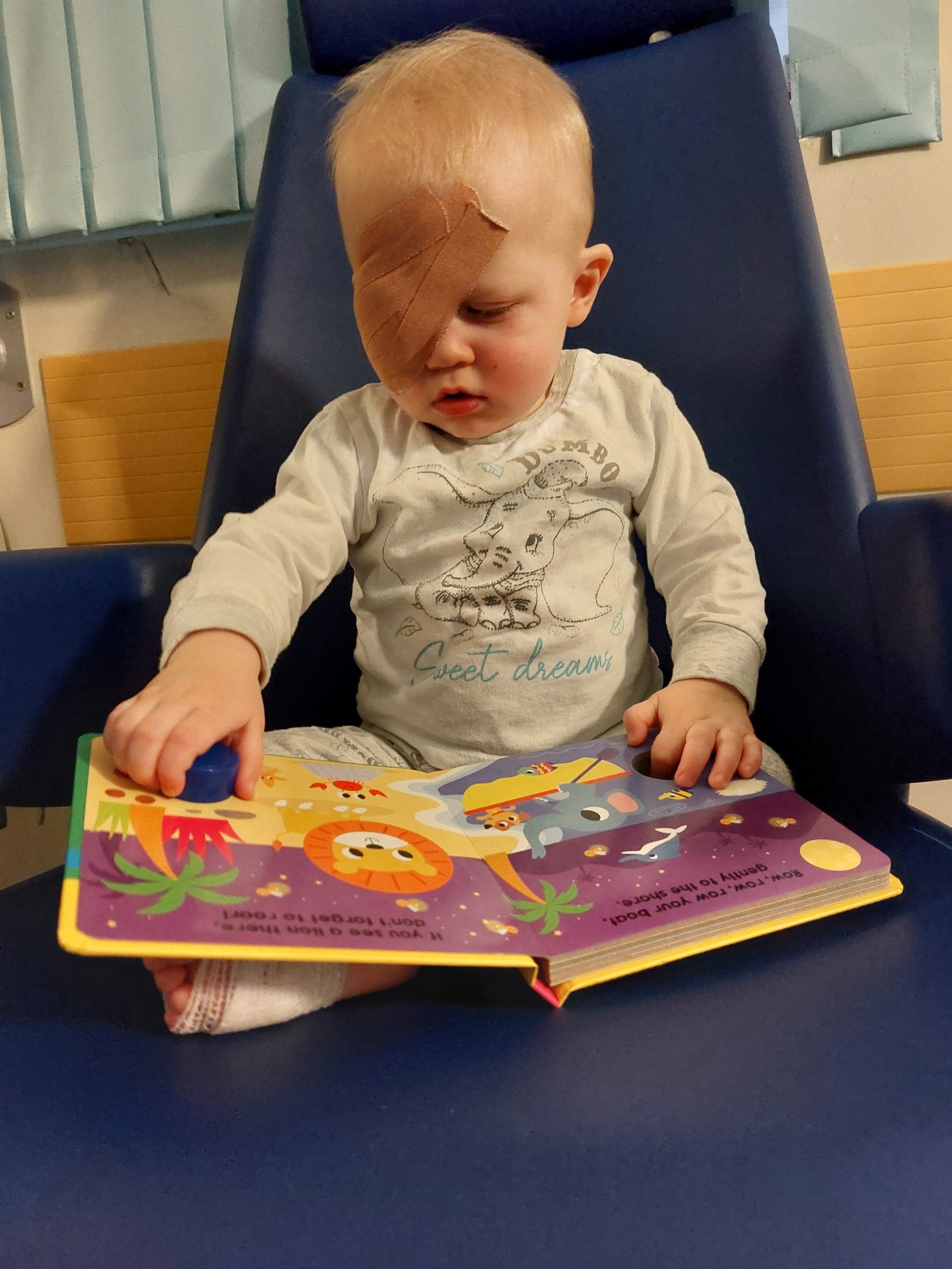 PostOpReading AJ reading after his operation with a board book and bandage on his eye.