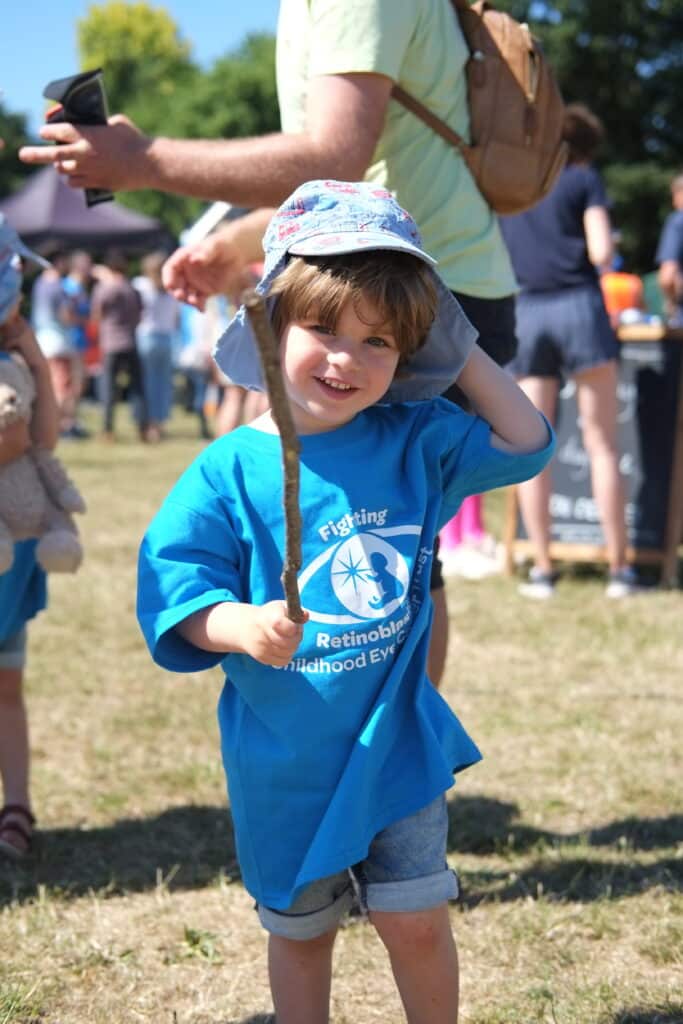 A happy child holding a stick with a CHECT T shirt on