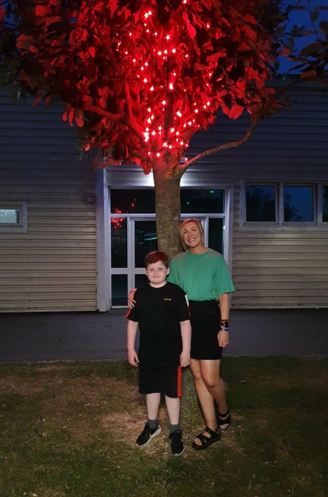 Sam stood next to a glowing tree with a child