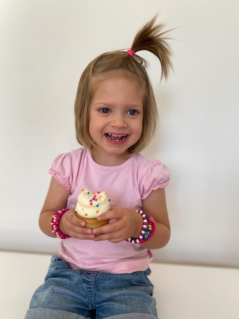 Isla smiling with a cupcake after treatment for retinoblastoma - eye cancer