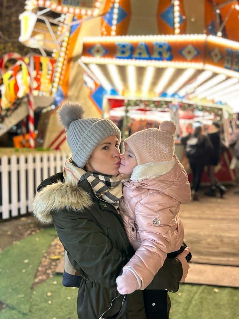 Olivia with her mum in front of a fairground after being diagnosed with retinoblastoma