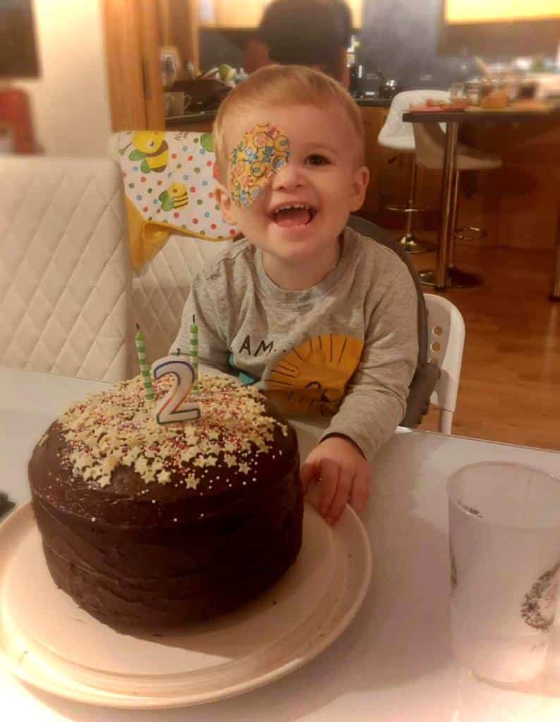 Cian sat with a birthday cake with a '2' candle