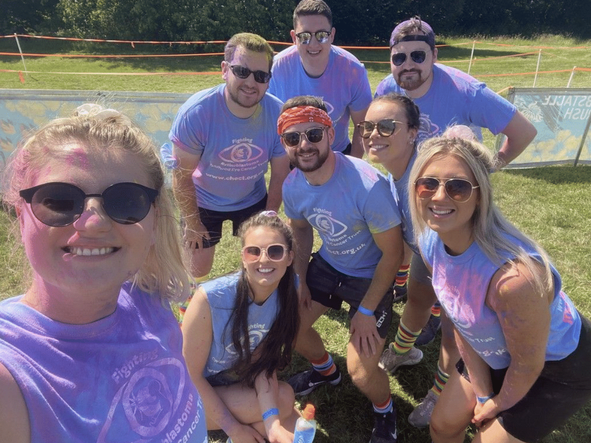 A group of friends crouching to take a selfie together after completing a colour run for Childhood Eye Cancer Trust