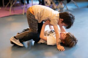 Two boys are rolling on the floor
