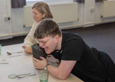 Young adult laughing whilst doing object handling at kelham island museum