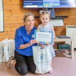 Lena with a child who is holding their CHECT Champion certificates