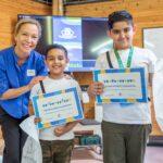 Lena with two child who are holding their CHECT Champion certificates