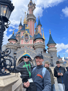 Andrew and his son at disneyland in front of the castle