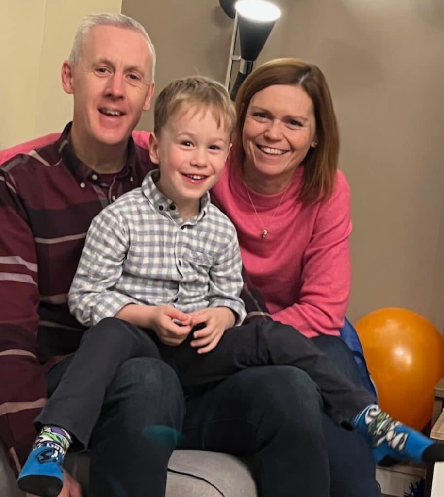 Kirsteen and Stephen smiling with their grandson