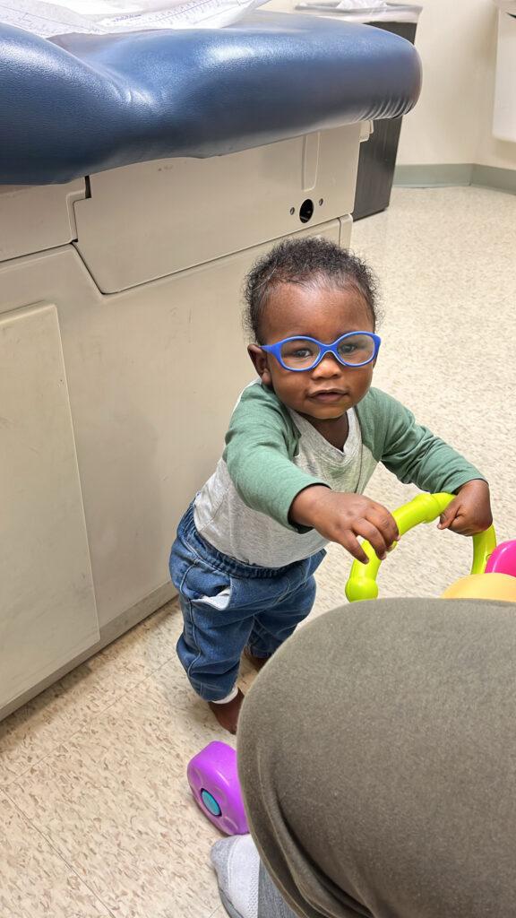 Kaois is walking with a walker. He has blue glasses on