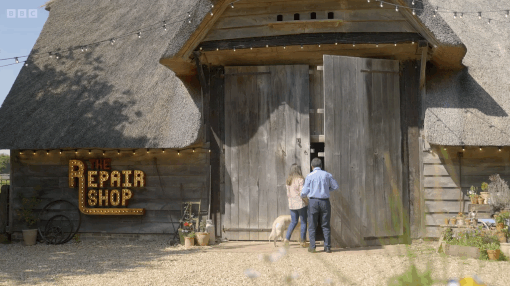 Hannah, her dad and guide dog Wendy are walking into a barn. The barn says 'The Repair Shop'